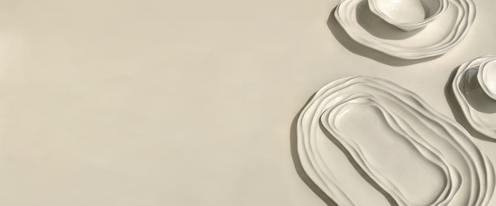 White sculptural ceramic tableware in a warm, neutral setting